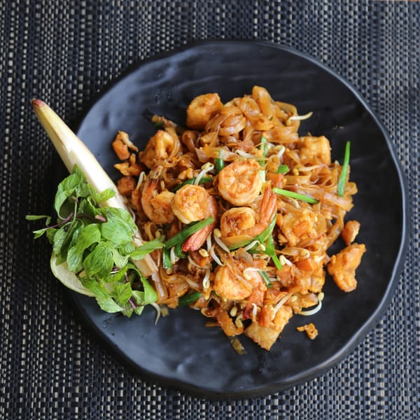 Ginger Asian Kitchen's Pad Thai with shrimp, noodles, bean sprouts, and green onions, garnished with mint.