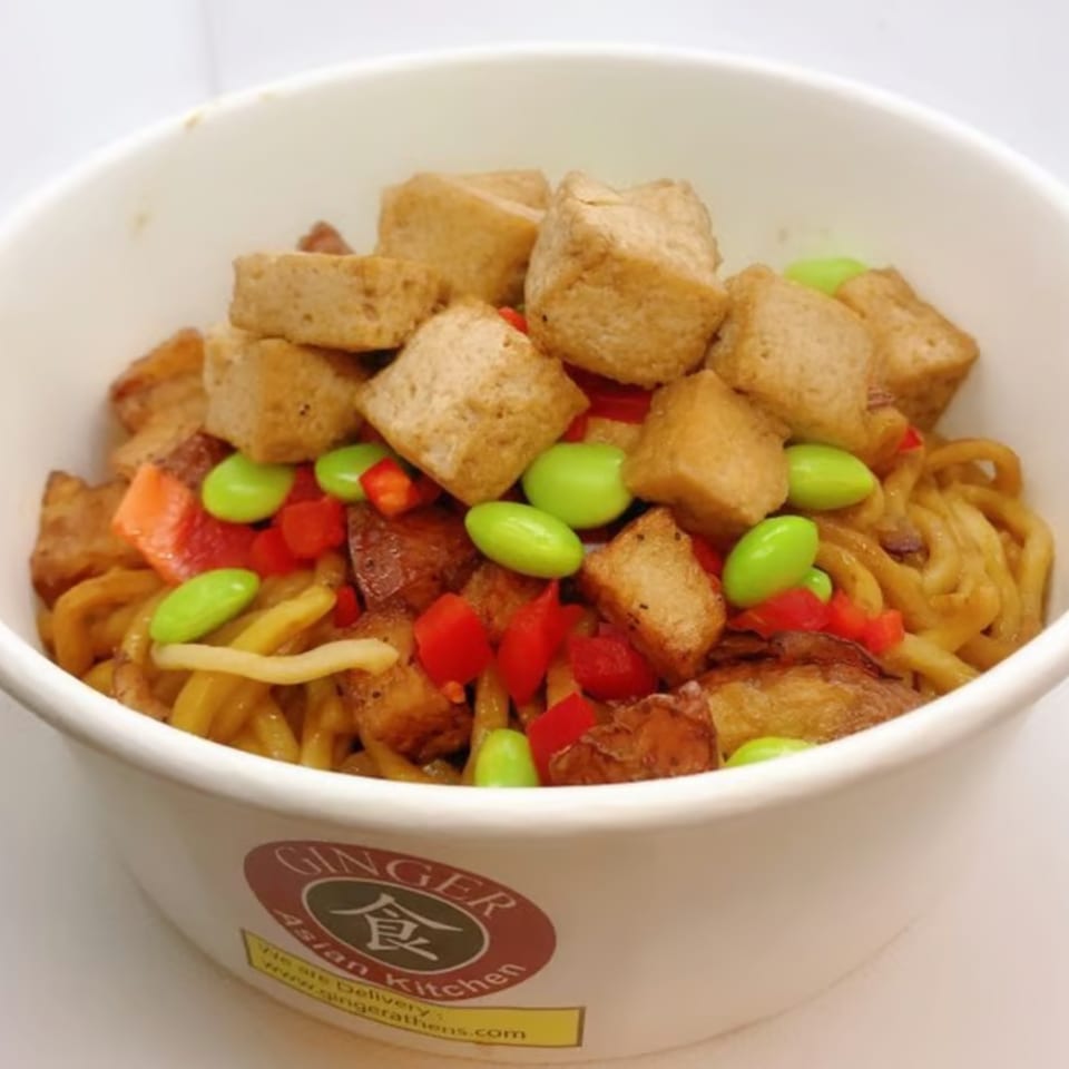 Ginger Asian Kitchen noodles with tofu, edamame, and red peppers in a white bowl.