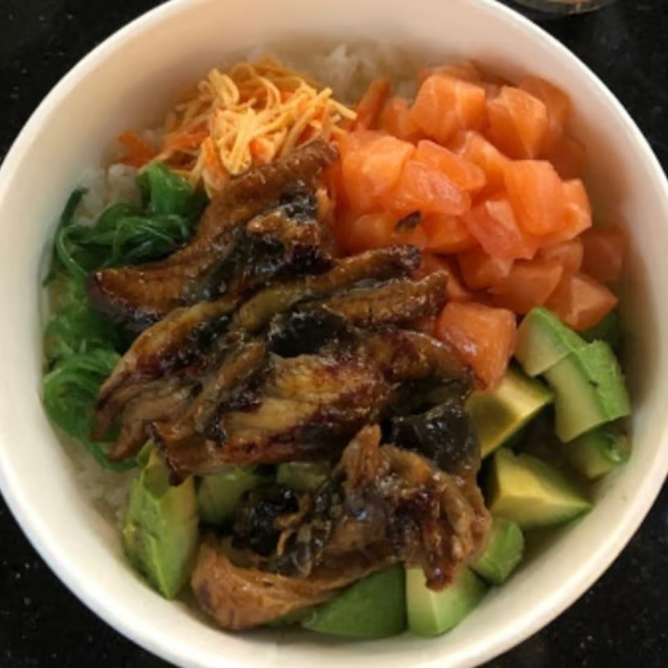 A Ginger Asian Kitchen poke bowl with eel, salmon, avocado, seaweed, and shredded carrots over rice.
